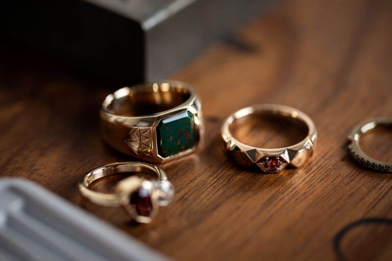 A close-up of various crafted rings with intricate designs displayed on a wooden surface.