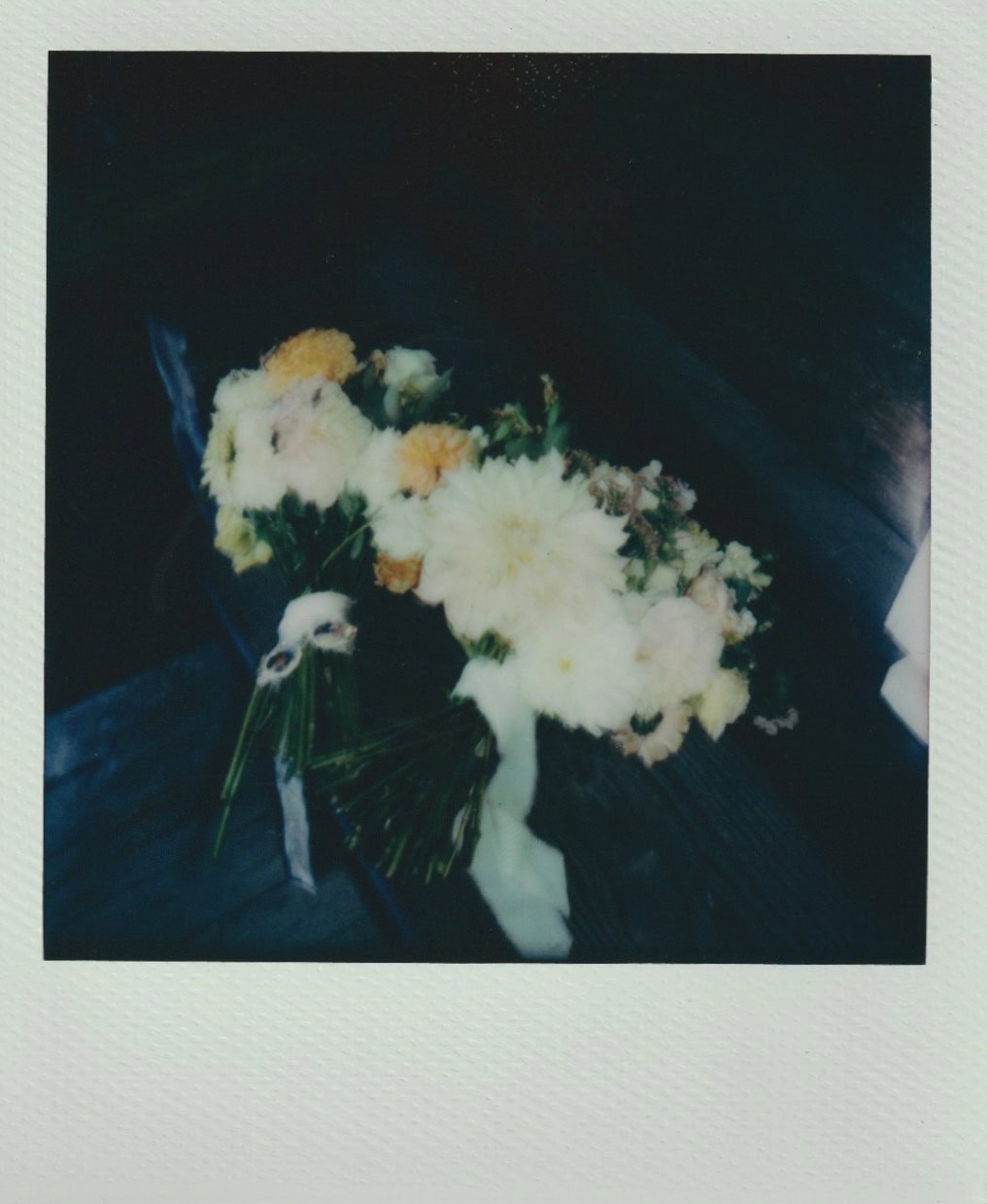 Two wildflower-style bouquets rest on a wooden bench, filled with white, peach, and cream blooms.