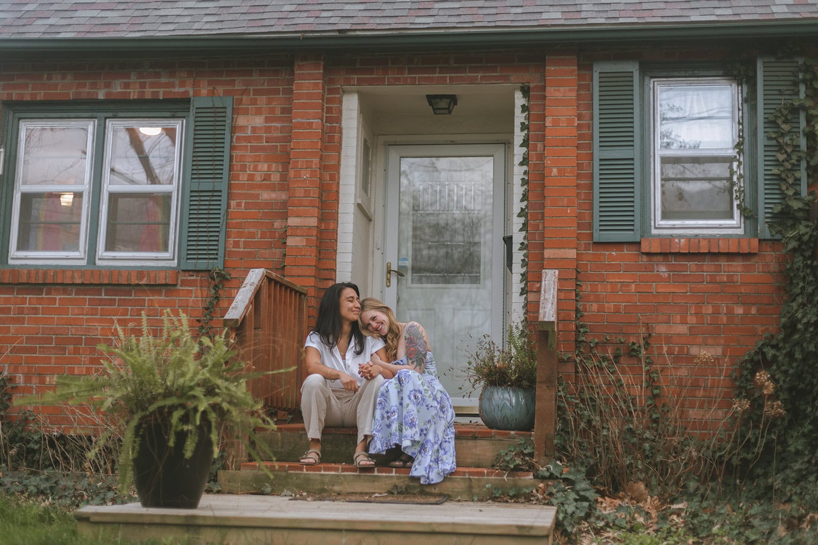 Couple sitting on front porch of brick home